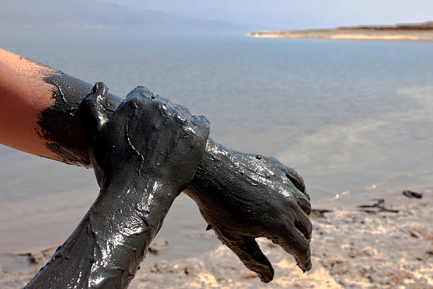 Woman hands smearing mud at the Dead Sea shore